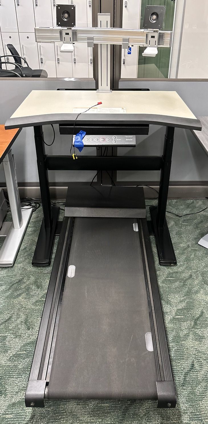 A treadmill is attached to a standing desk in an office.