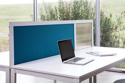 A laptop computer is sitting on a white desk in front of a window.