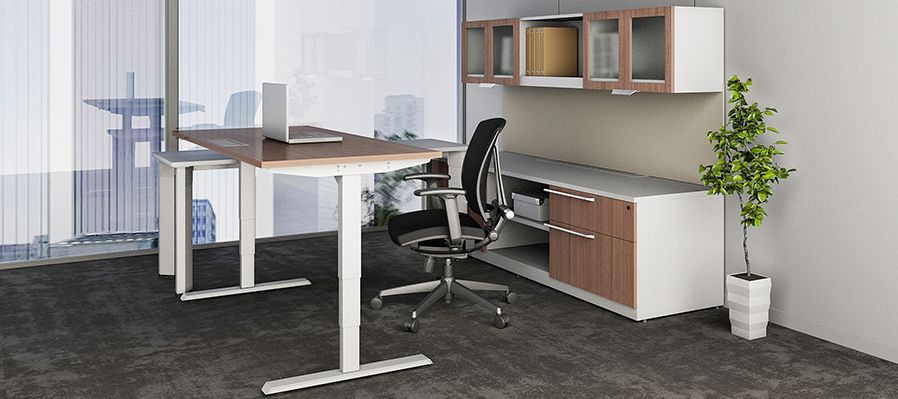 A standing desk with a laptop on it in an office.