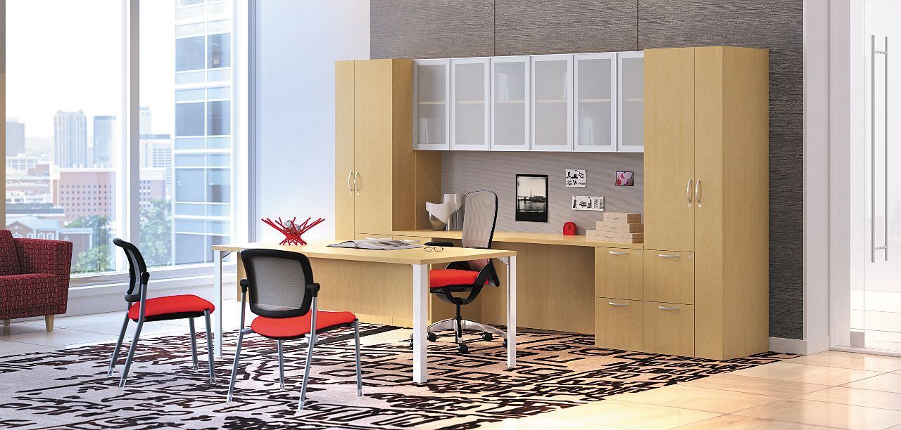 A room with a desk , chairs , cabinets and a rug.