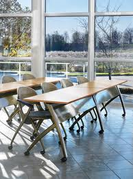 A row of tables and chairs in a room with a lot of windows.