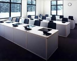 A classroom with a lot of tables and chairs and a clock on the wall.