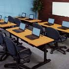 A classroom filled with tables and chairs filled with laptops.