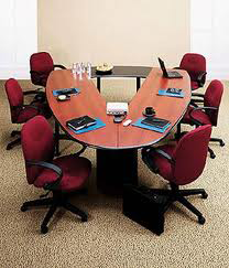 A conference room with a long wooden table and red chairs.
