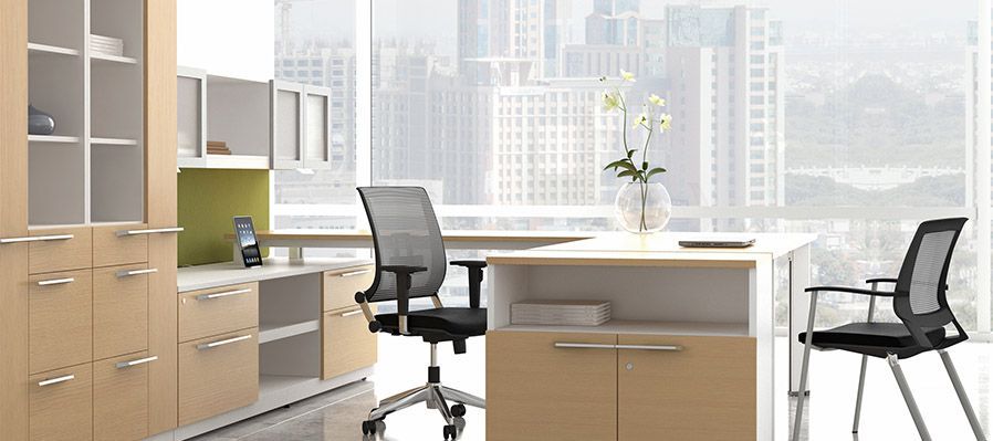 An office with a desk , chairs , cabinets and a large window.
