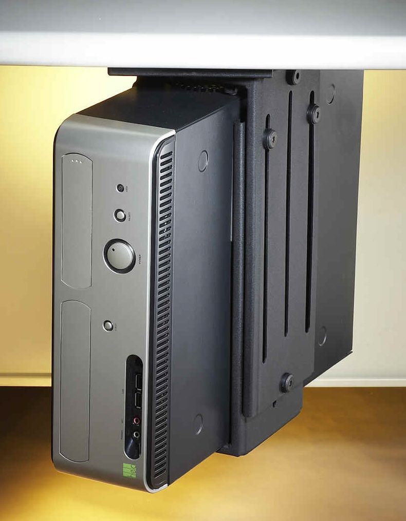 A small computer sitting under a desk with a bracket attached to it