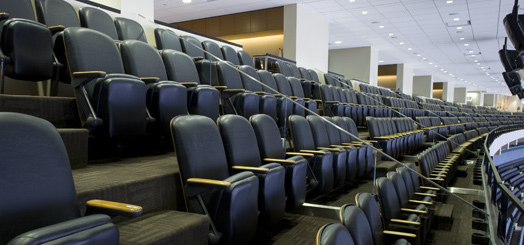 A row of empty seats in a stadium with stairs leading up to them.