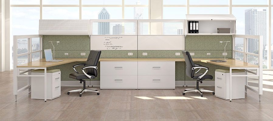 A cubicle with two desks and two chairs in an office.