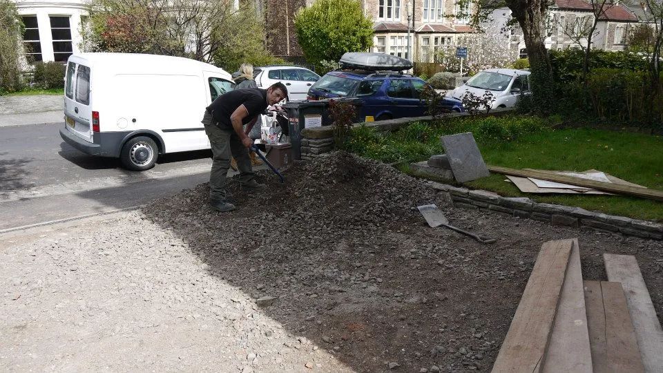 Urban Paving Bristol | A man is digging in the dirt in front of a white van