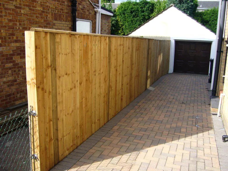 Urban Paving Bristol | A wooden fence along a brick driveway with a garage in the background