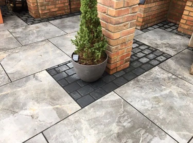 Urban Paving Bristol | A potted plant is sitting on a patio next to a brick wall.