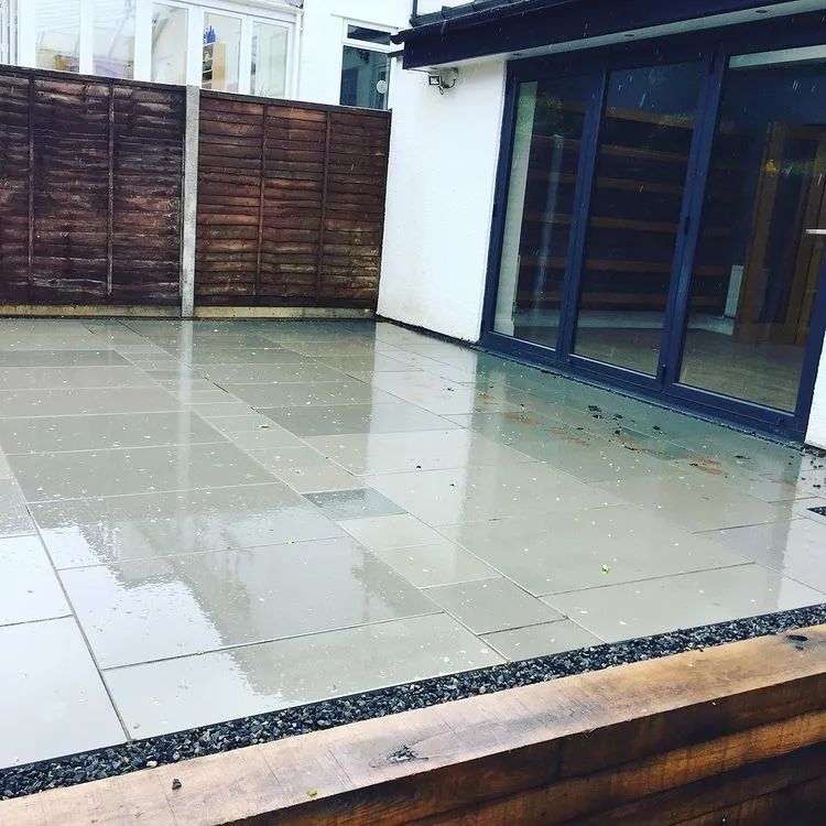 Urban Paving Bristol | A patio with tiles and a wooden fence in front of a house.