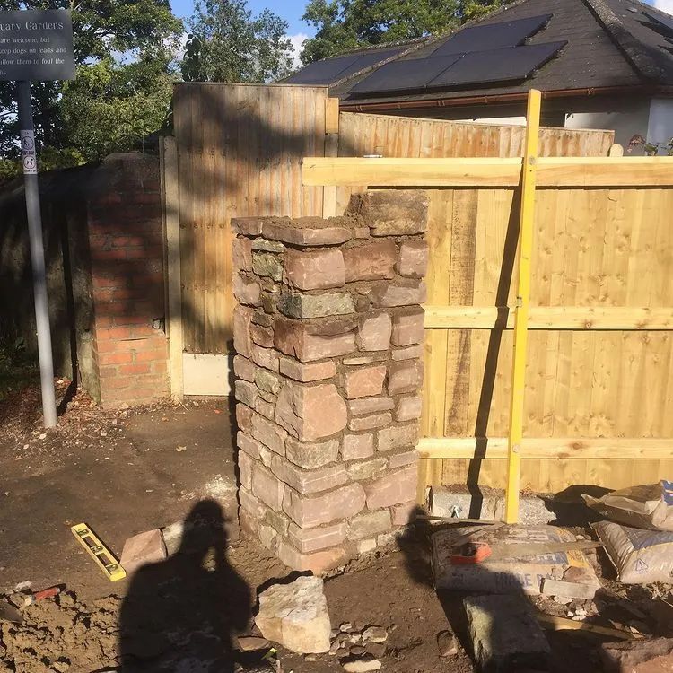 Urban Paving Bristol | A brick wall is being built next to a wooden fence.