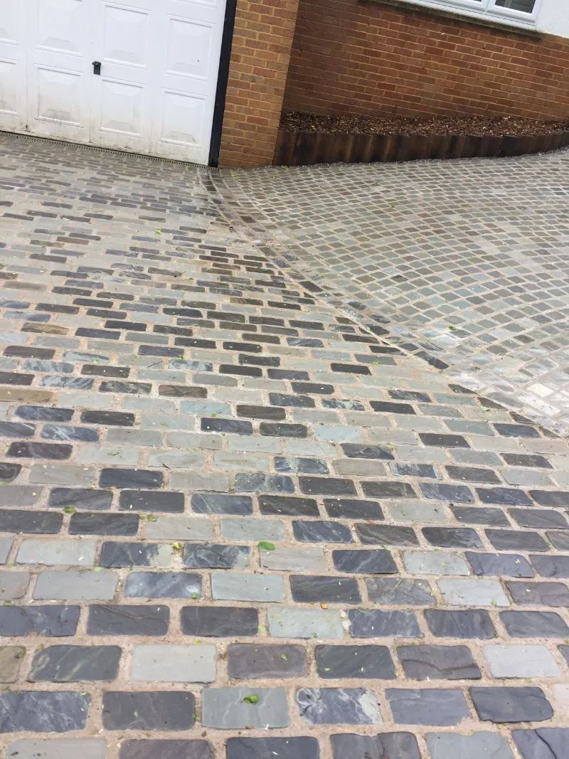 Urban Paving Bristol | A cobblestone driveway with a garage door in the background.
