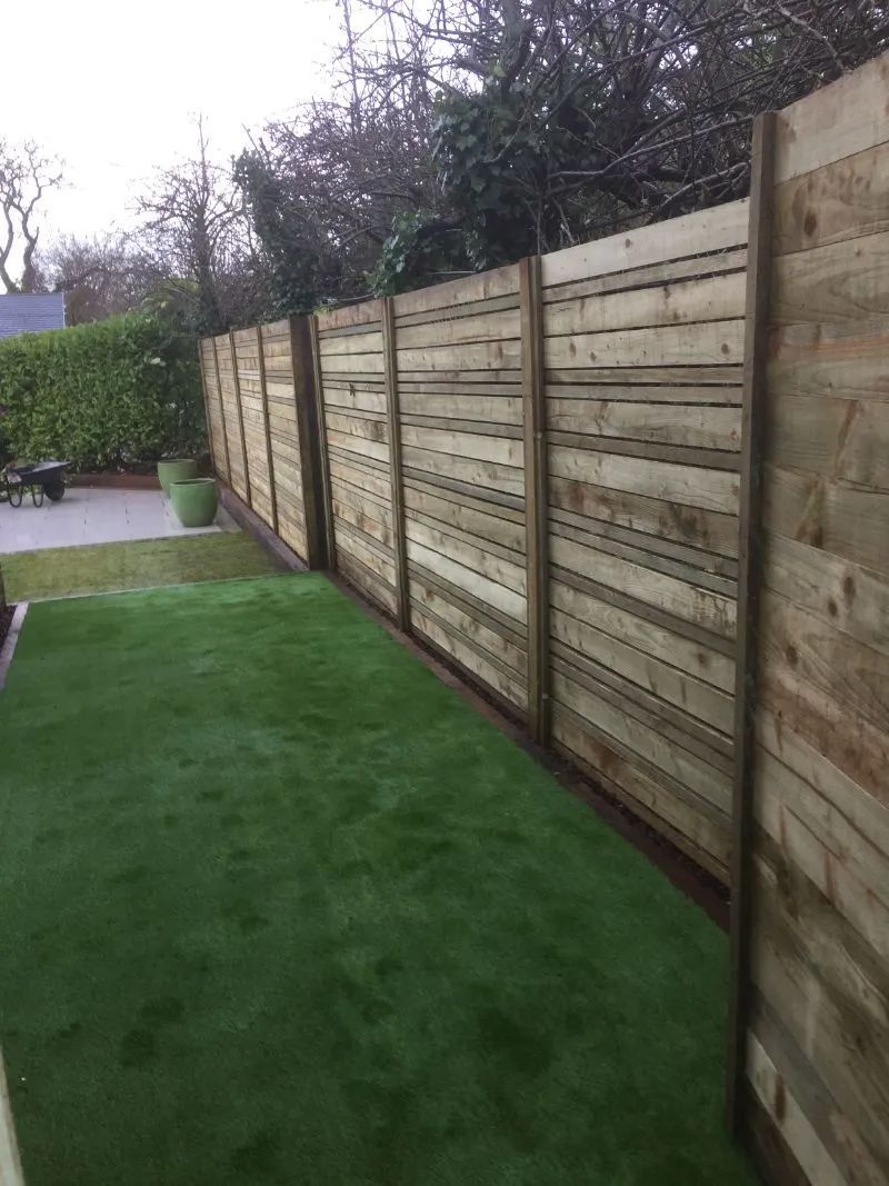 Urban Paving Bristol | A wooden fence surrounds a lush green lawn in a garden.