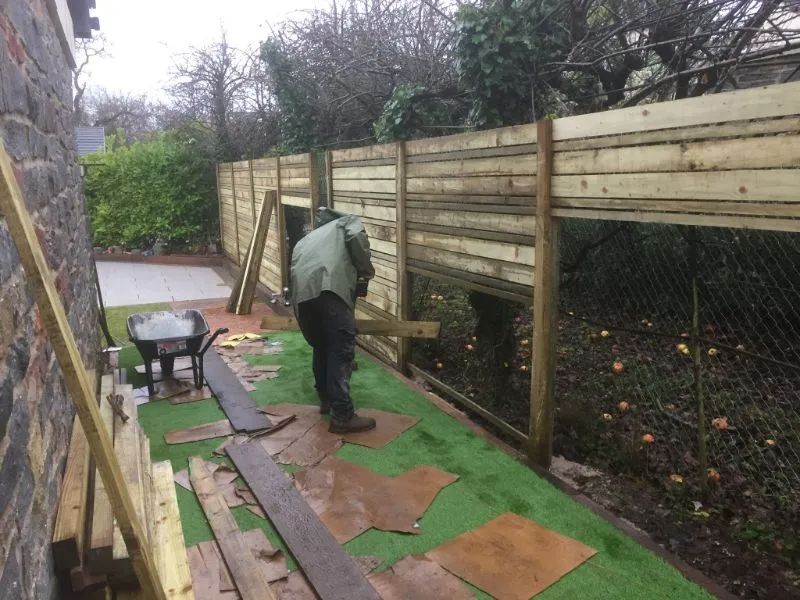 Urban Paving Bristol | A man is working on a wooden fence in a backyard.