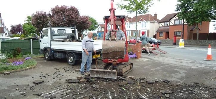 Urban Paving Bristol | A man is standing next to a small excavator in front of a truck.