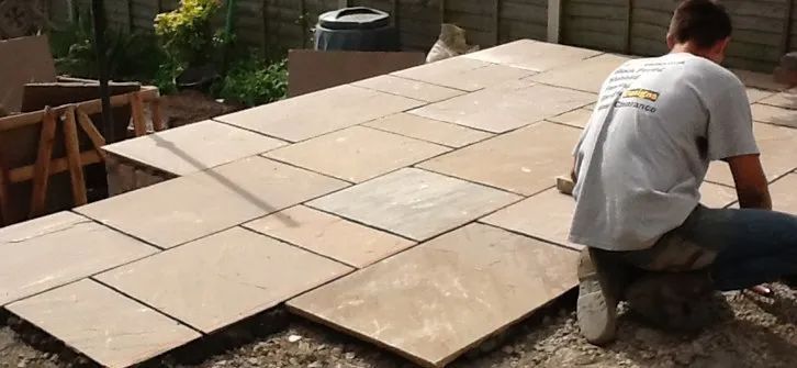 Urban Paving Bristol | A man is laying a patio in a back garden.