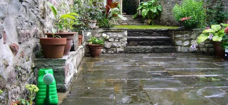Urban Paving Bristol | A patio with potted plants and a green watering can.