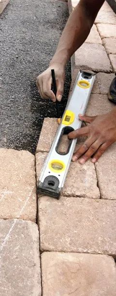 Urban Paving Bristol | A person is using a level to measure a brick walkway.