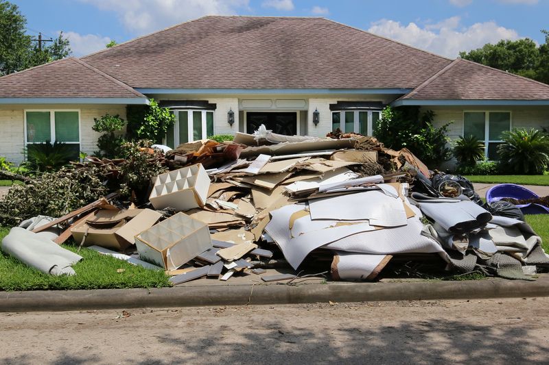 A large pile of trash is in front of a house.