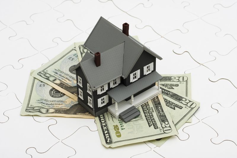 A model house is sitting on top of a pile of money