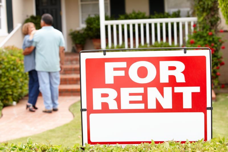 A couple standing in front of a for rent sign