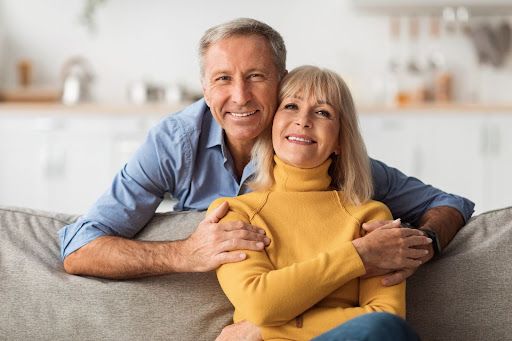 A man and a woman are sitting on a couch hugging each other.