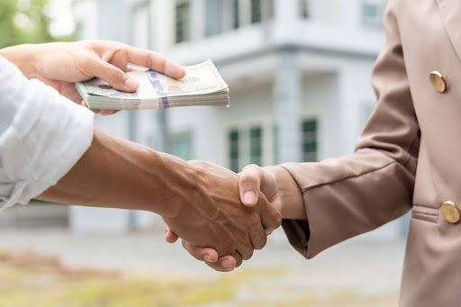 A man is handing a woman a stack of money while shaking her hand.