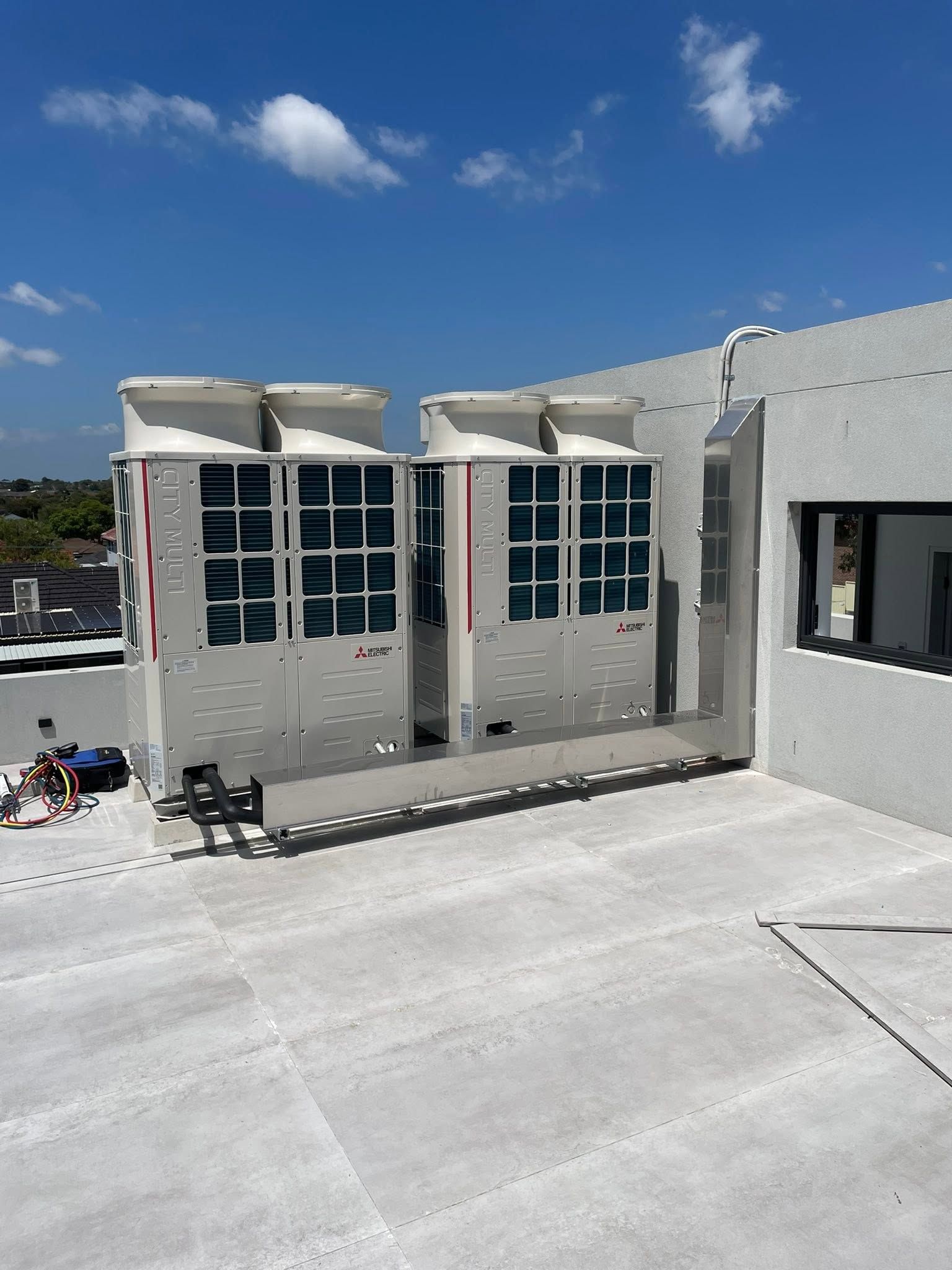 Rooftop construction site with gray concrete walls, large window openings, and a blue sky overhead