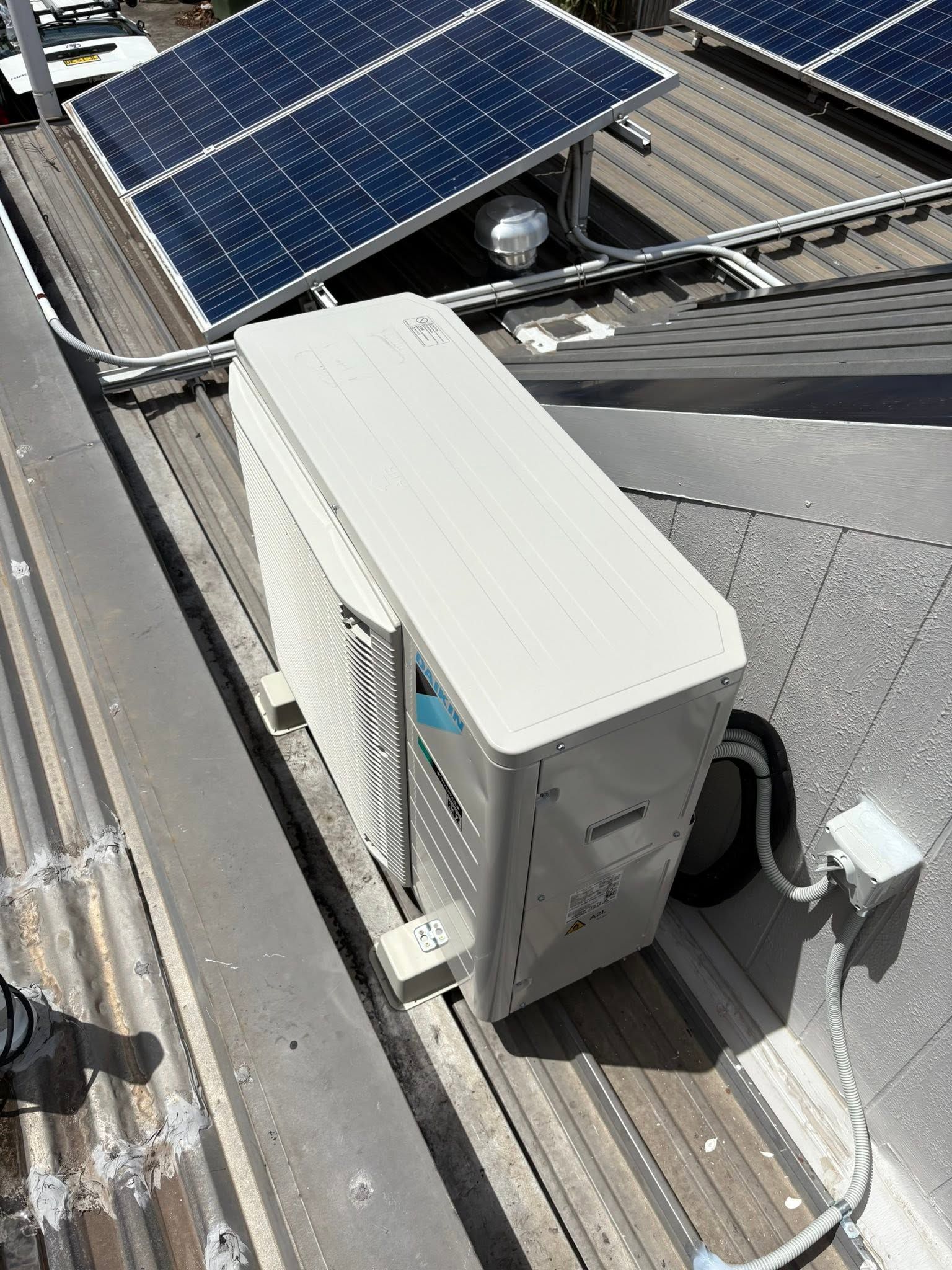 Solar panel and rooftop HVAC unit on a corrugated metal roof.