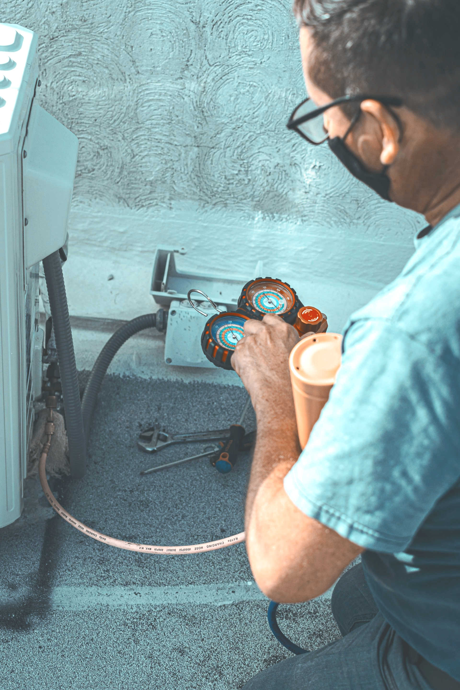 Technician inspecting pressure gauges and hoses on industrial equipment in a utility room