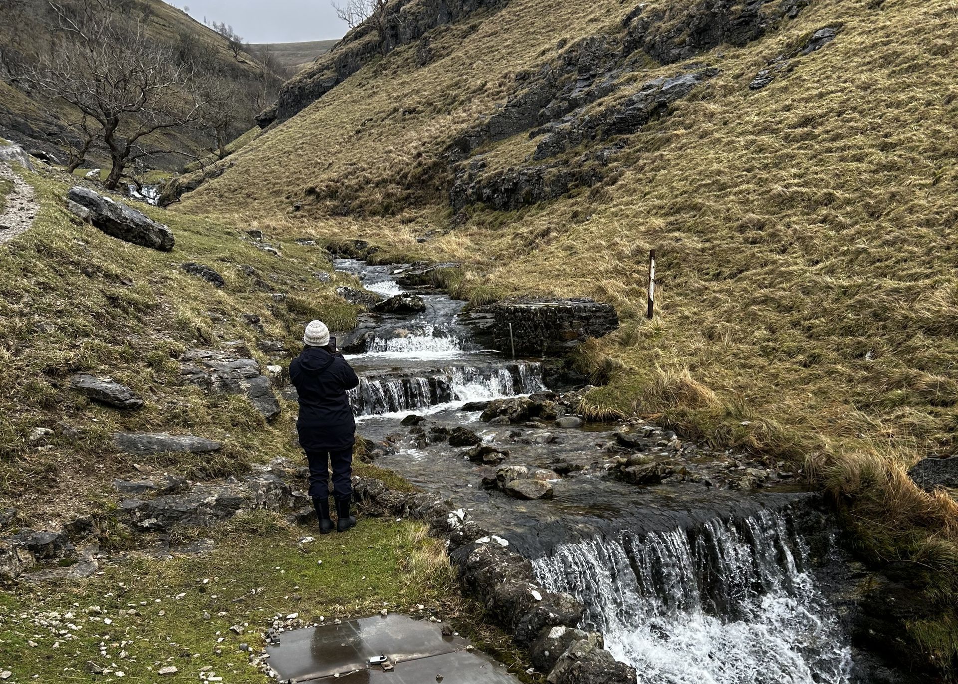a woman reviewing weirs in a village beck.