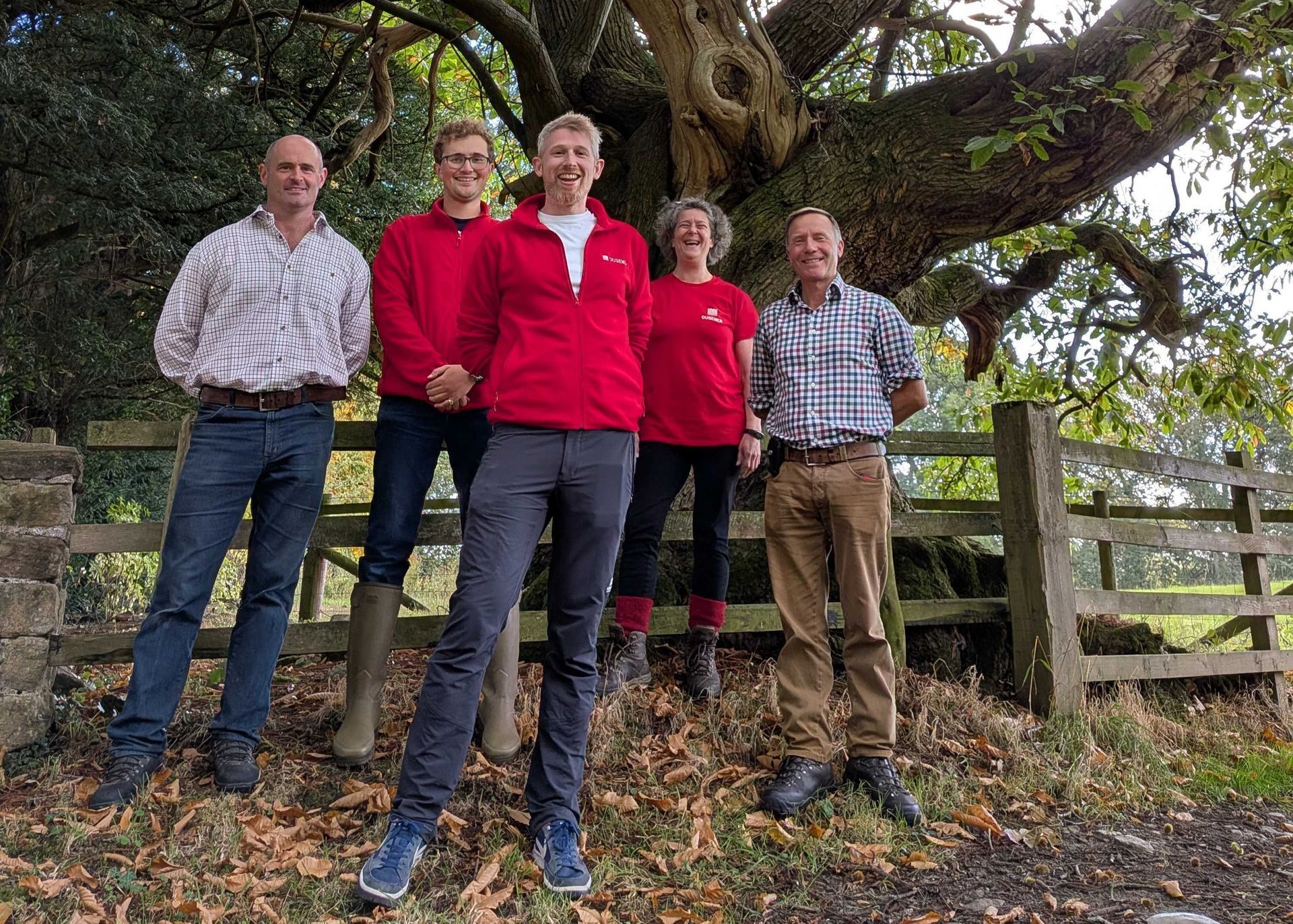Five people stood in front of a tree smiling a the camera.