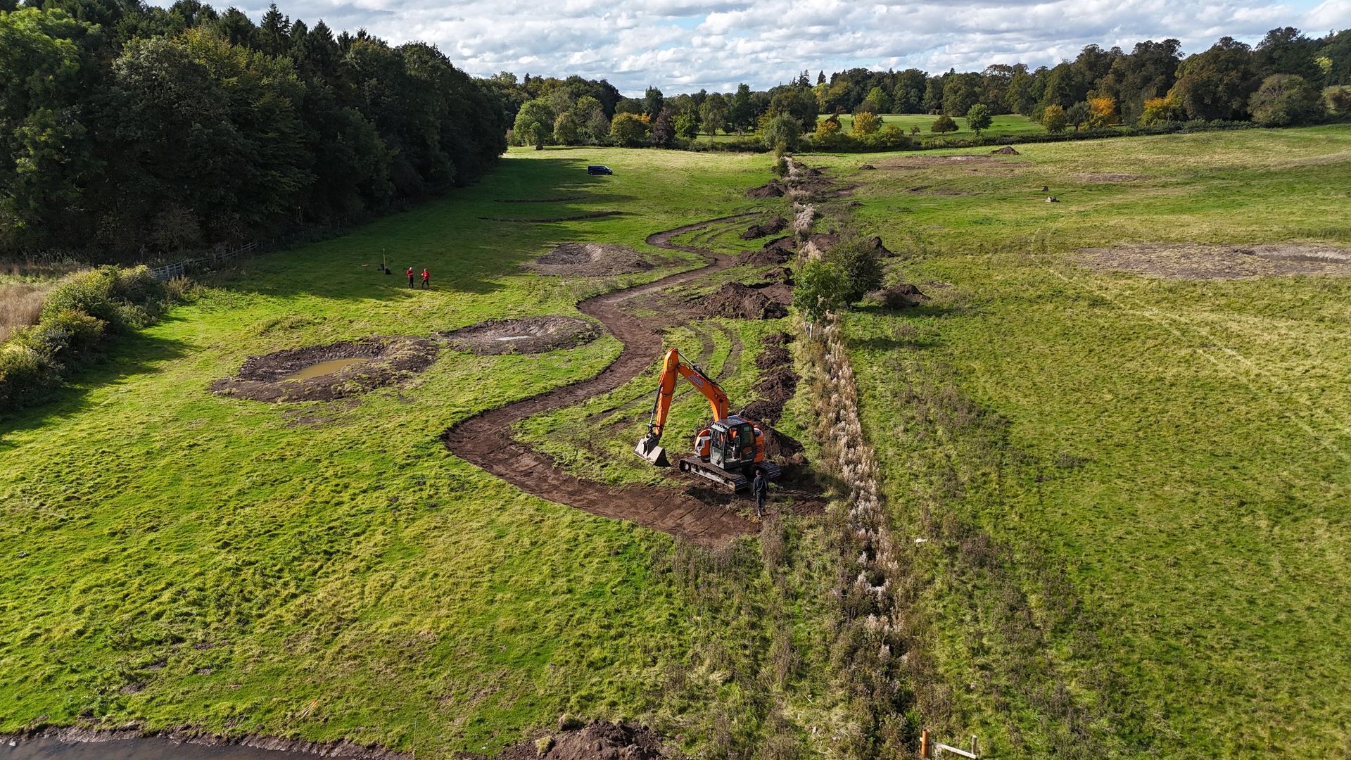 A digger creating a new channel for the re-wiggled stream adjacent to its old straight course.