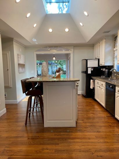 Bright kitchen with island, hardwood floors, stainless appliances, and skylights over a dining area.