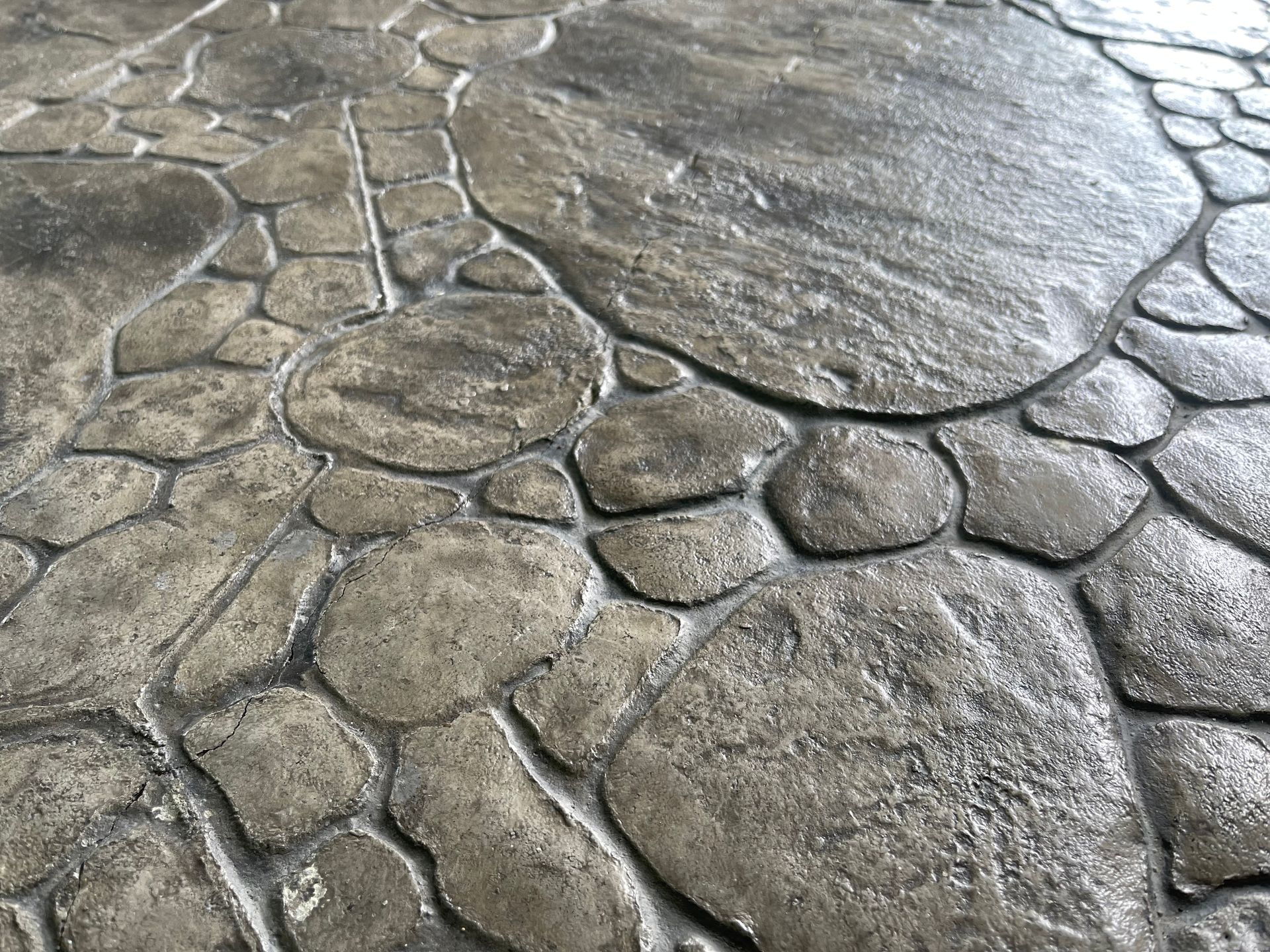 Cracked gray stone pavement with irregular textured slabs and white grout lines