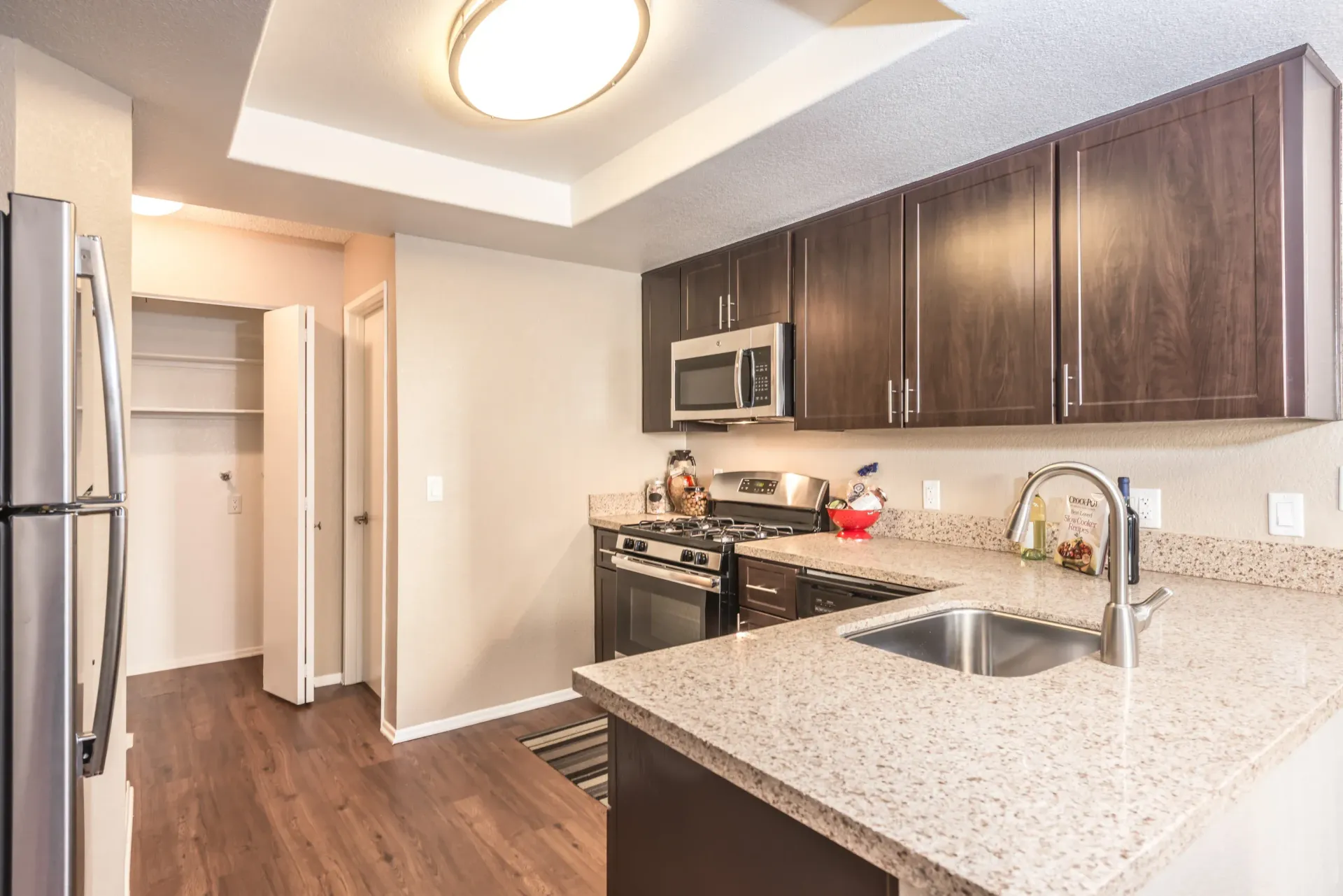 Kitchen in an apartment with dark wood cabinets and granite countertops at Sonora at Alta Loma apartments in Alta Loma, CA.