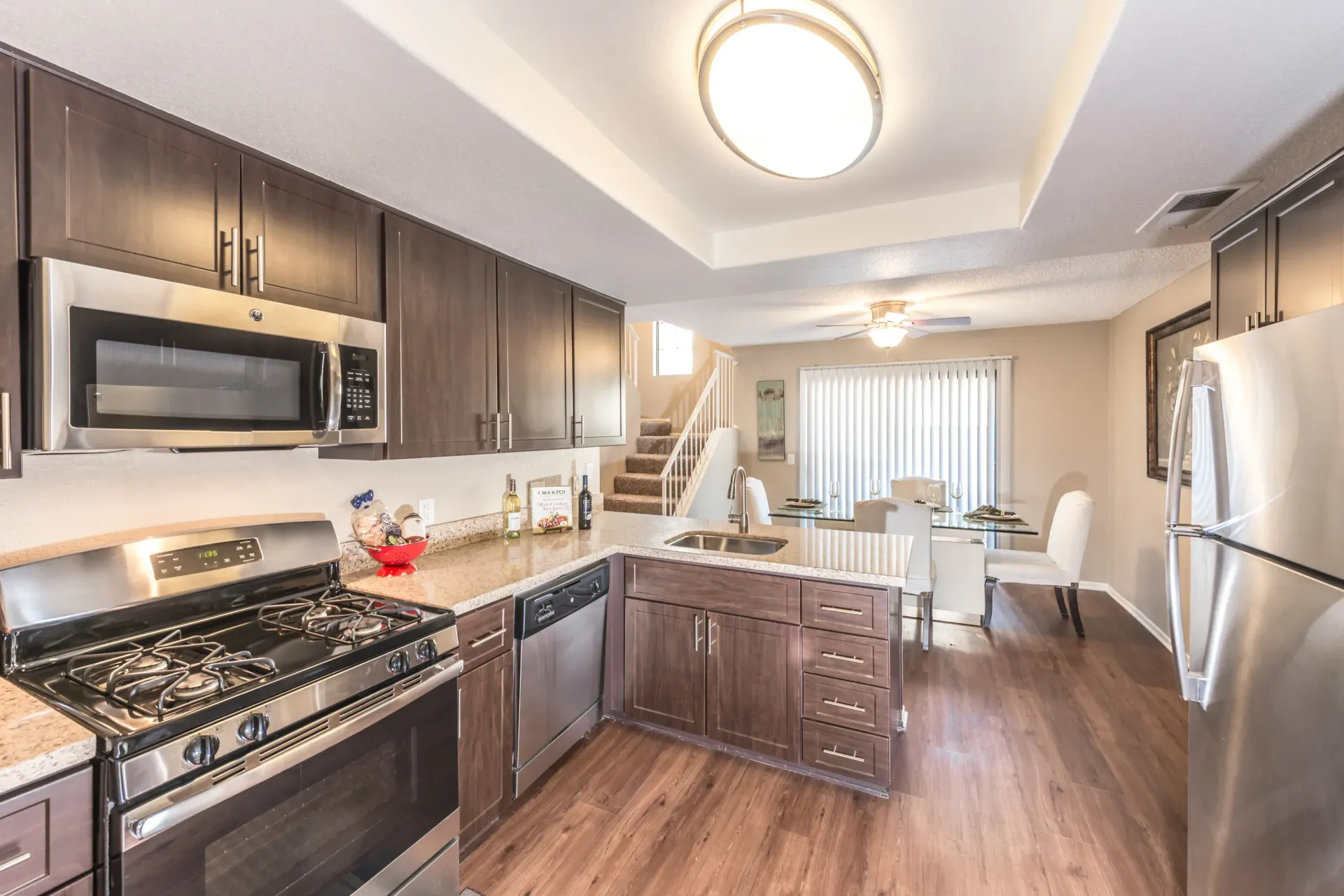 Modern apartment kitchen with stainless steel appliances and dark wood cabinets at Sonora at Alta Loma apartments in Alta Loma, CA.