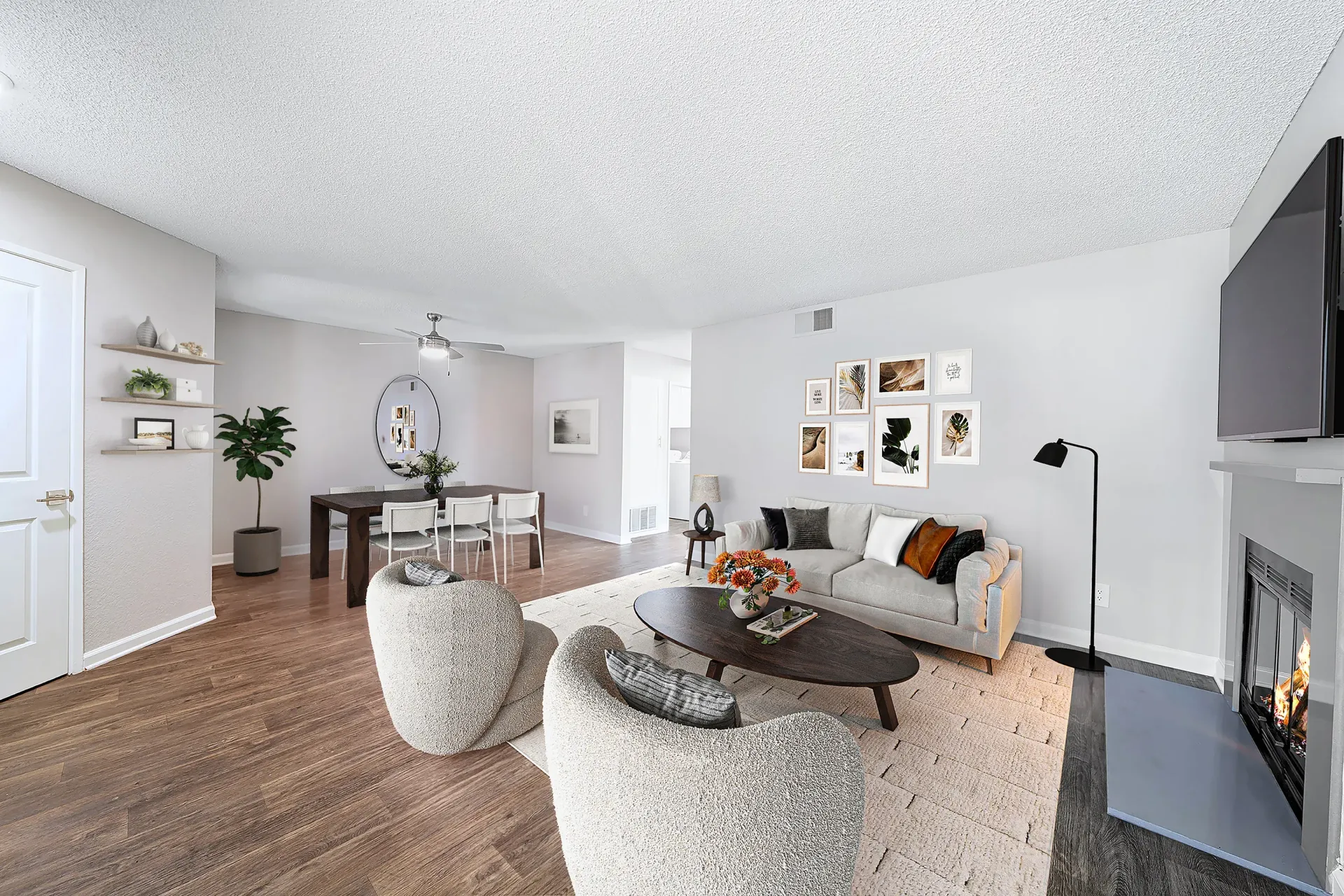 Open-concept living room in a modern apartment with sofa, lounge chairs, fireplace, and dining area at Sonora at Alta Loma apartments in Alta Loma, CA.