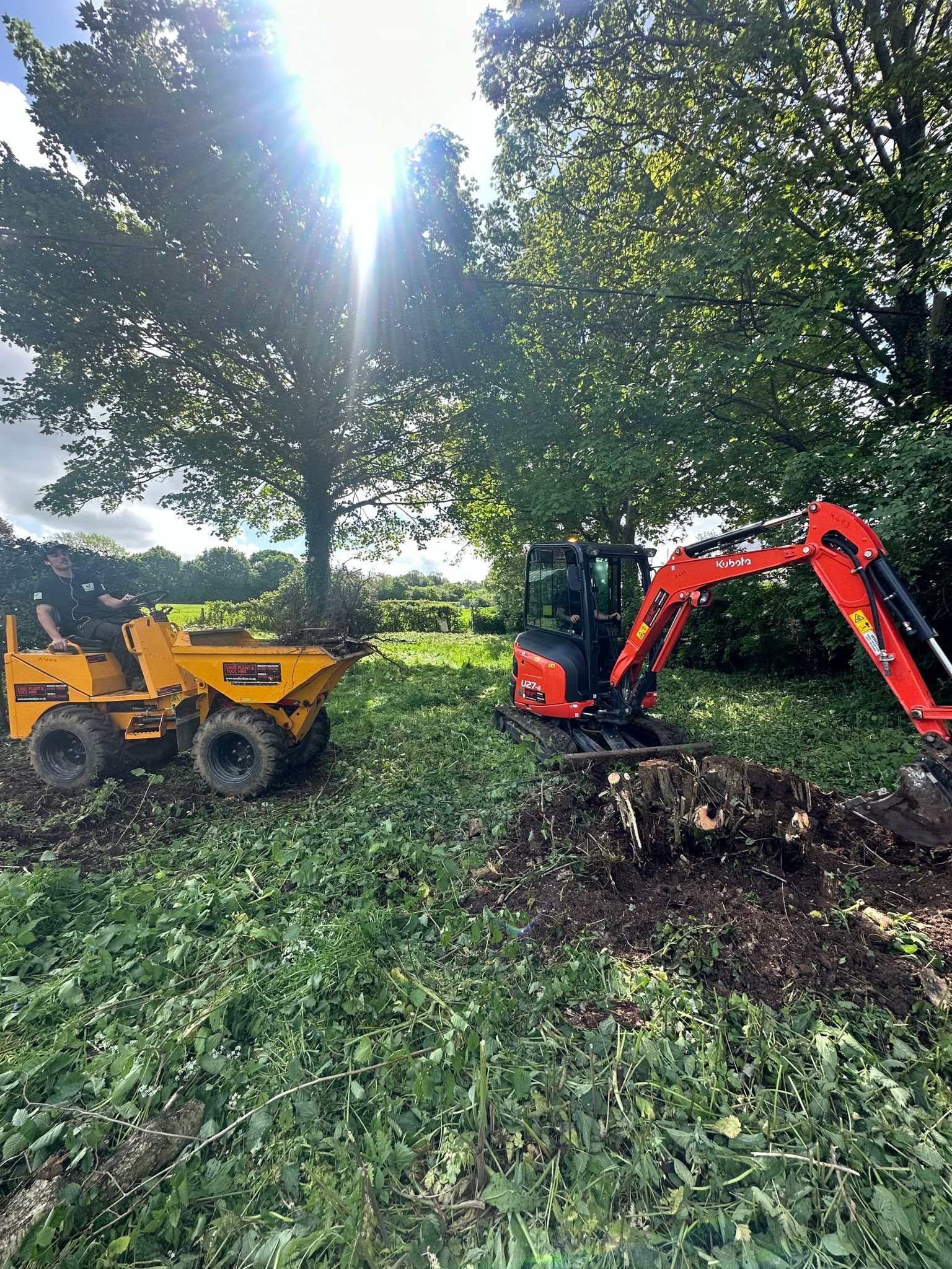 A dump truck and an excavator are sitting in a field.