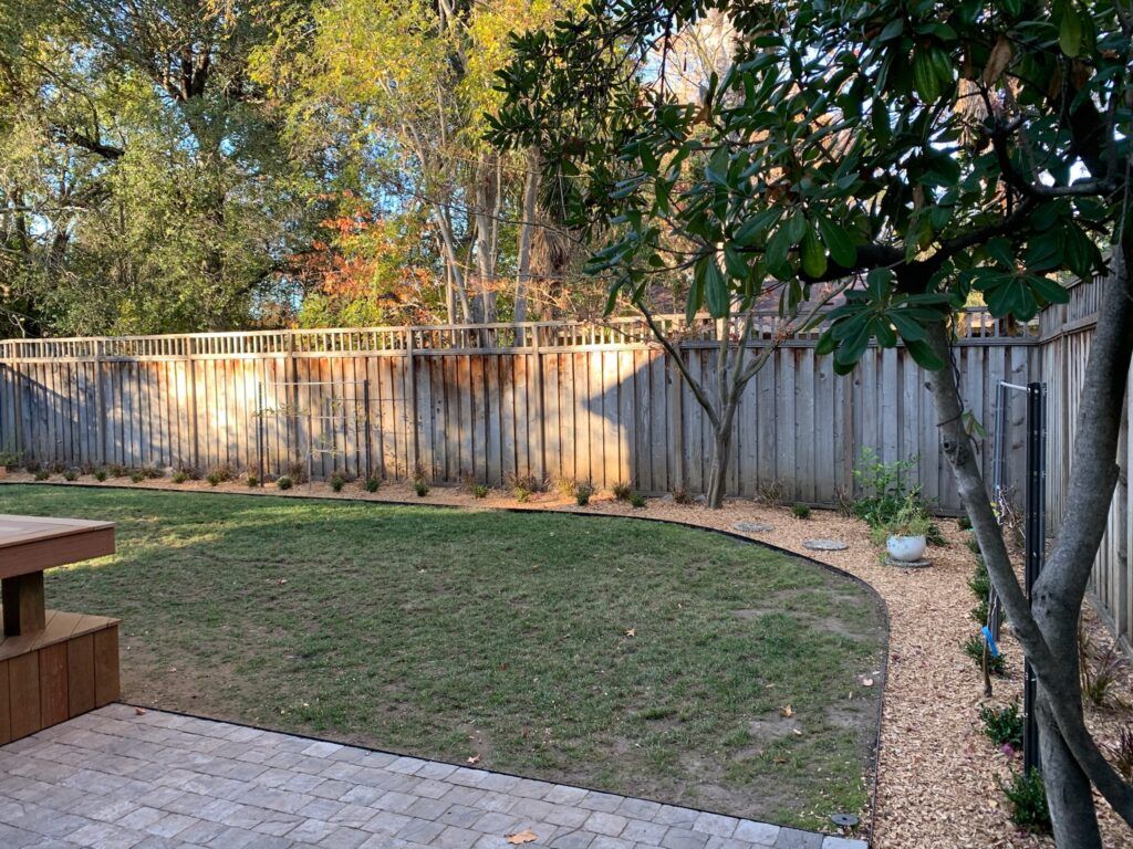 A backyard with a wooden fence and a picnic table.