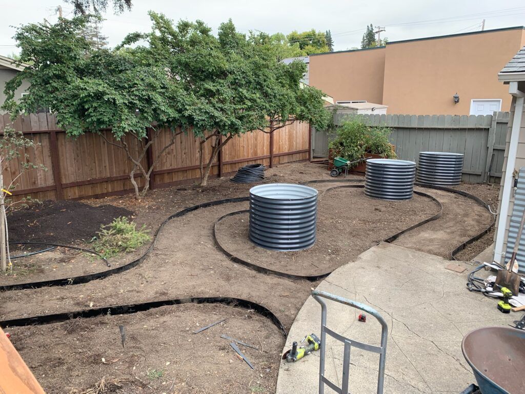 A backyard with a wooden fence and a concrete walkway.