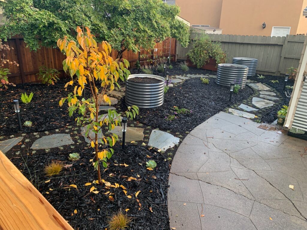 A backyard with a concrete walkway and a wooden fence