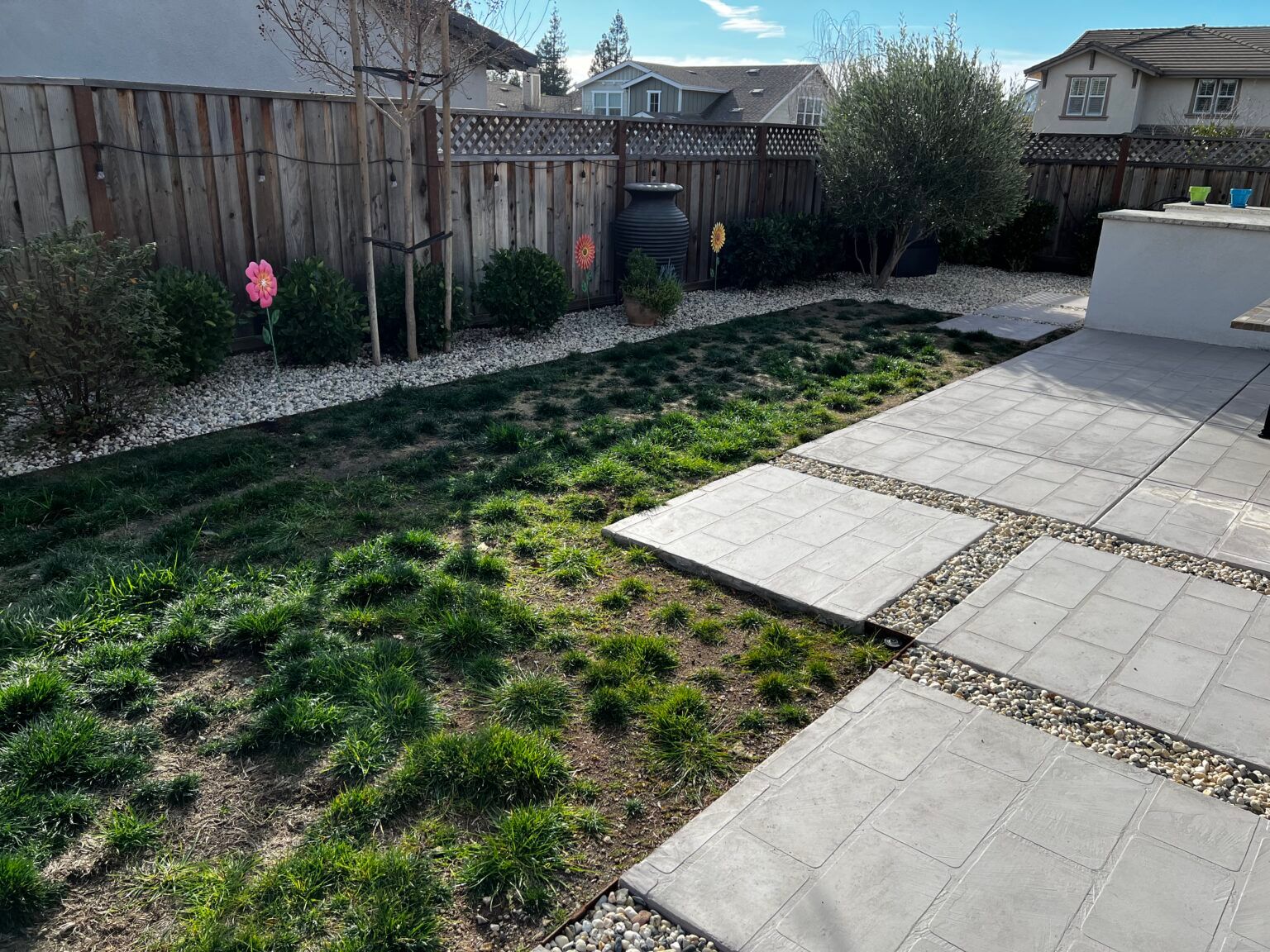 A backyard with a fence and a patio with a lot of grass.