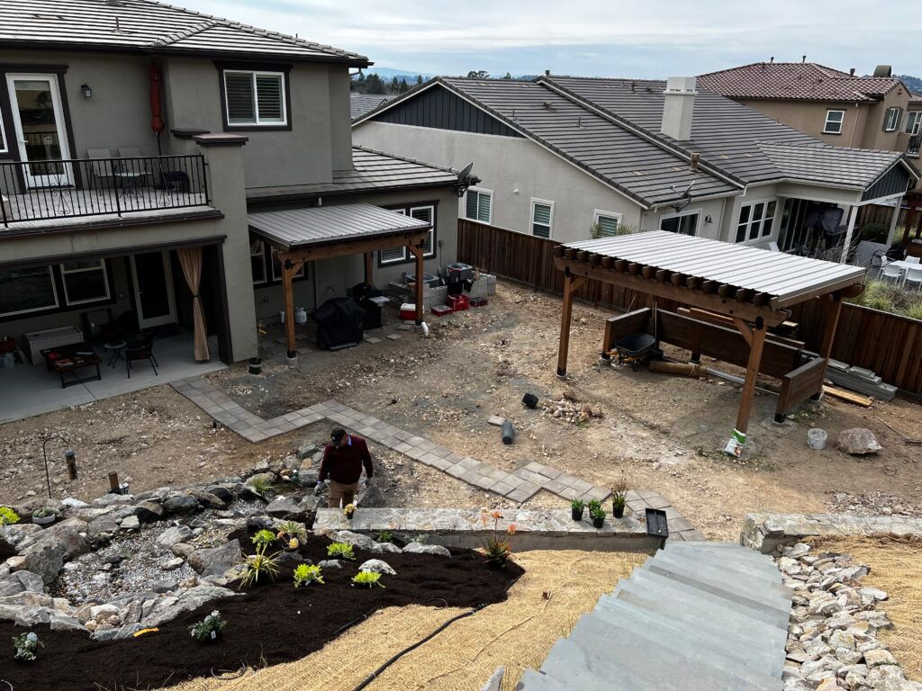 A man is standing in front of a house in a backyard.