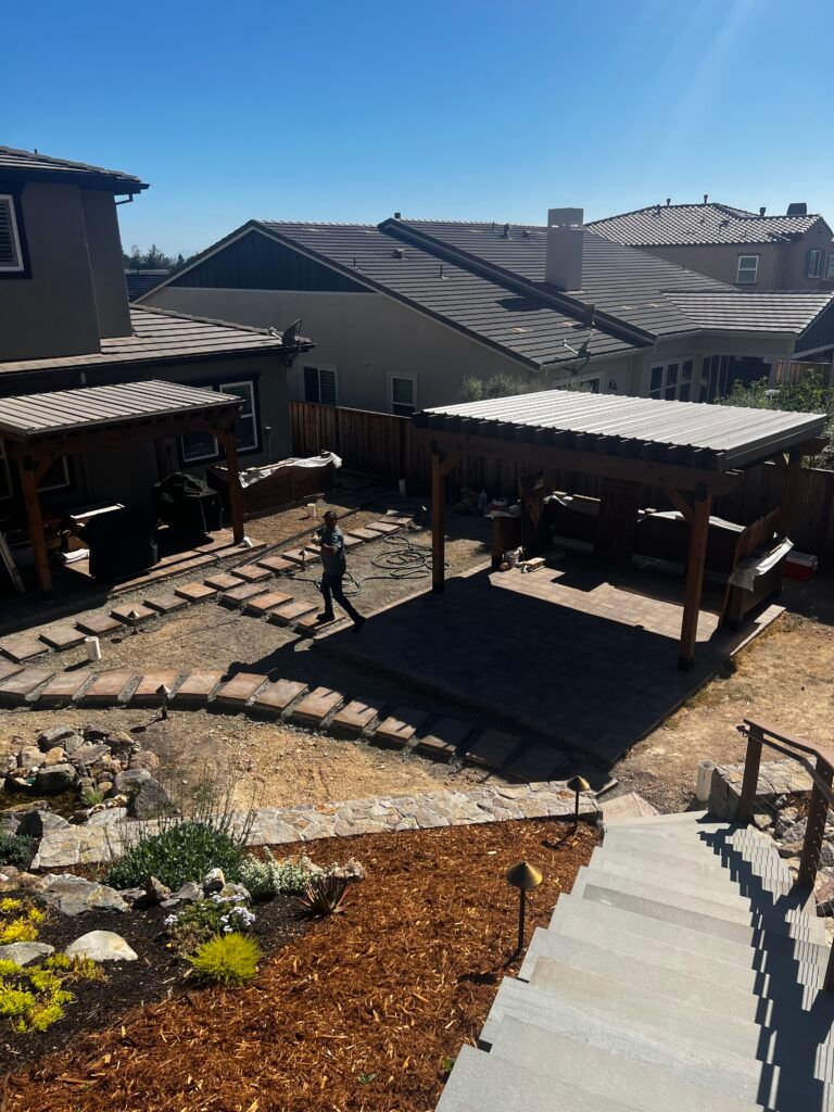 A person is walking in a backyard with a pergola and stairs.
