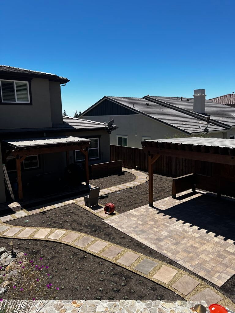 A house with a patio in front of it and a carport in the backyard.