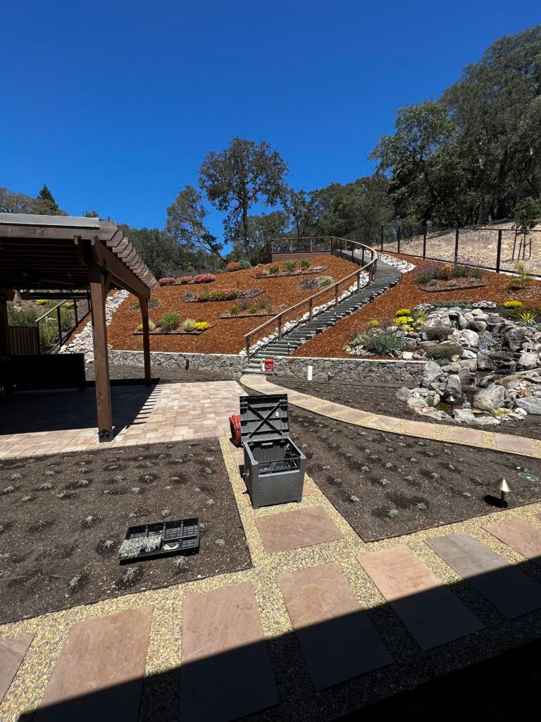 A garden with a waterfall and stairs in the background.