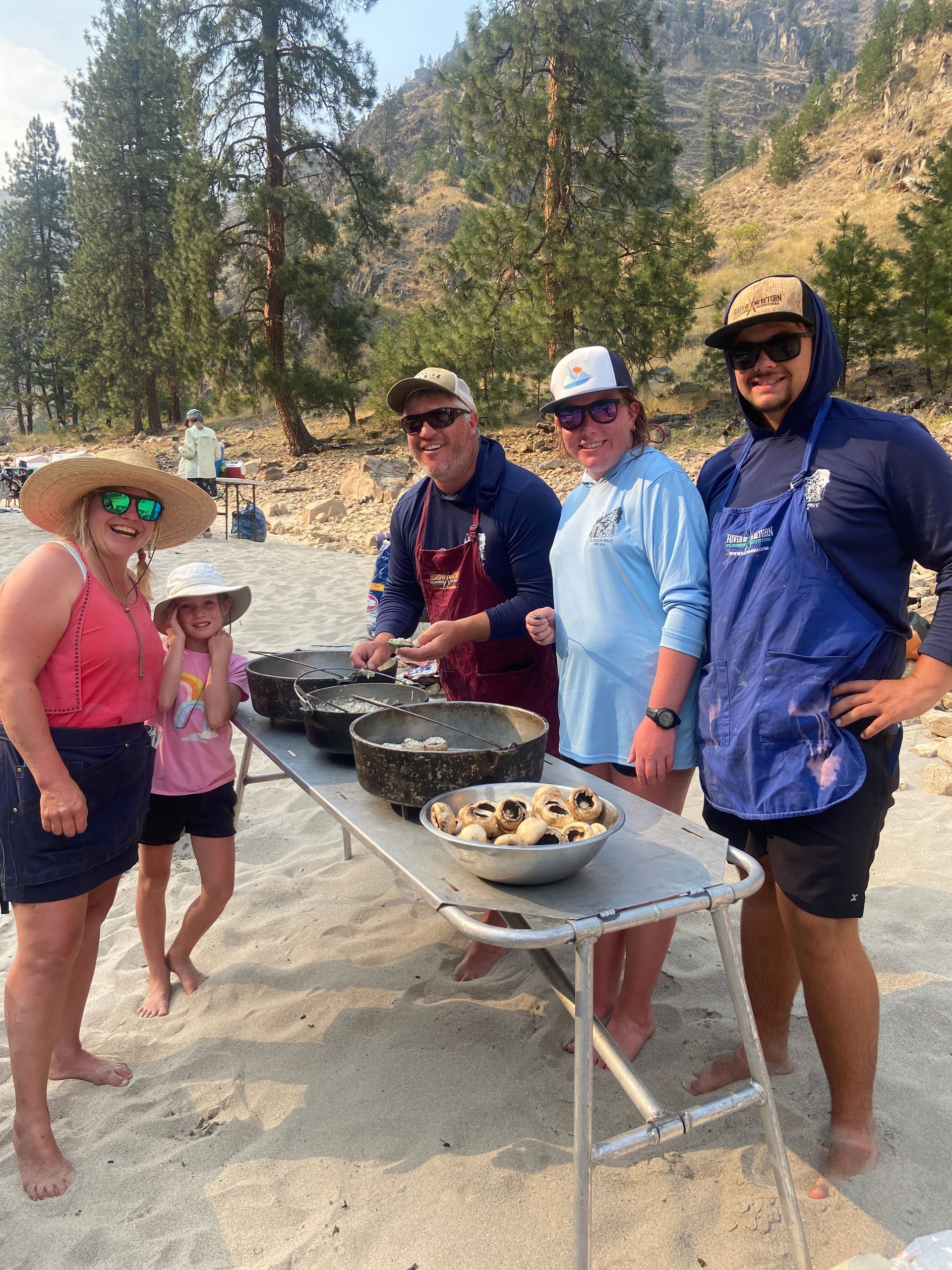 A group of people are standing around a table with bowls of food on it.